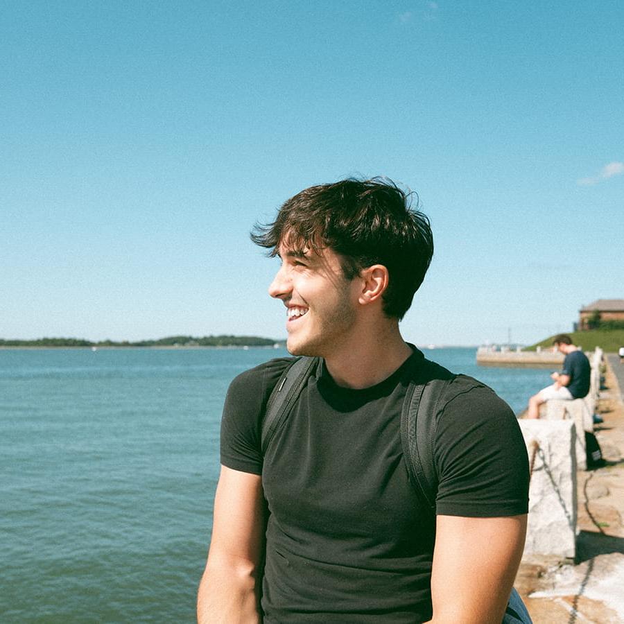 Student looks at water from harborwalk at UMass Boston.