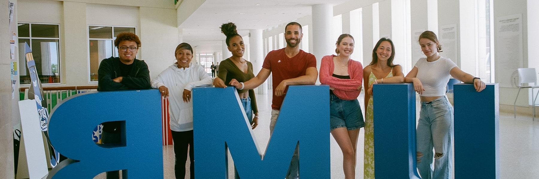 Students pose with sculptural UMB letters in Campus Center.